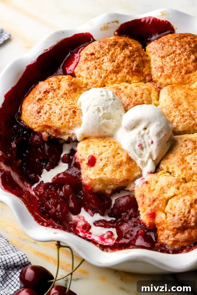 cherry cobbler with some slices removed and ice cream melting