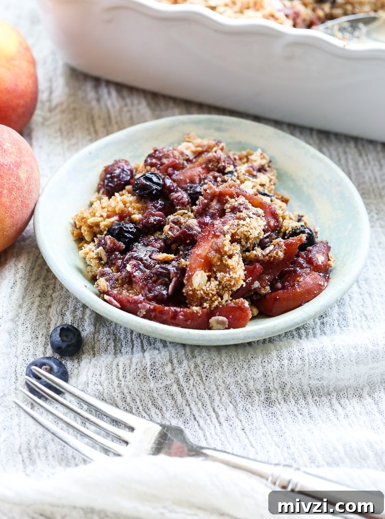 a close up shot of one serving of Peach Blueberry Crisp in a small dish