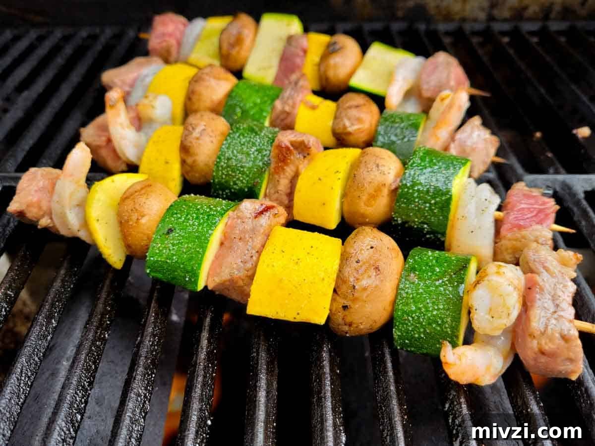 Surf and Turf Shrimp & Steak Kabobs Recipe for Grilling 6 beef, shrimp, and veggie kabobs cooking on a grill.