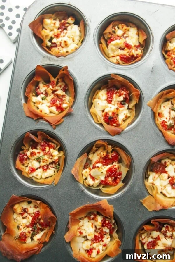 Close up of baked sundried tomato feta cups in a mini muffin tin.