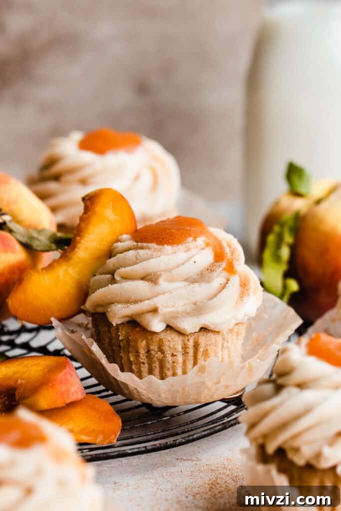Peach Cupcakes with Cinnamon Cream Cheese Frosting — Summer Dessert Recipe 2 Peach cupcakes topped with silky frosting and peach filling on a vintage wire rack.