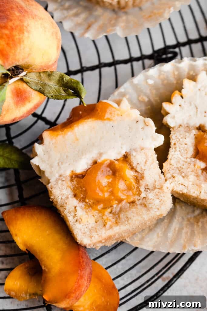 Peach Cupcakes with Cinnamon Cream Cheese Frosting — Summer Dessert Recipe 9 A top down view of a cupcake cut in half, revealing the peach pie filling.