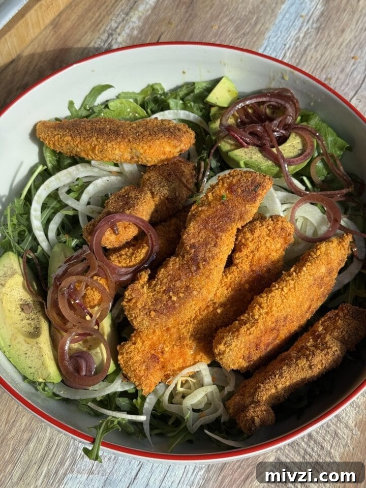 Protein-Packed Baked Chicken Fingers for Muscle Growth 7 baked chicken fingers on a salad in a white bowl