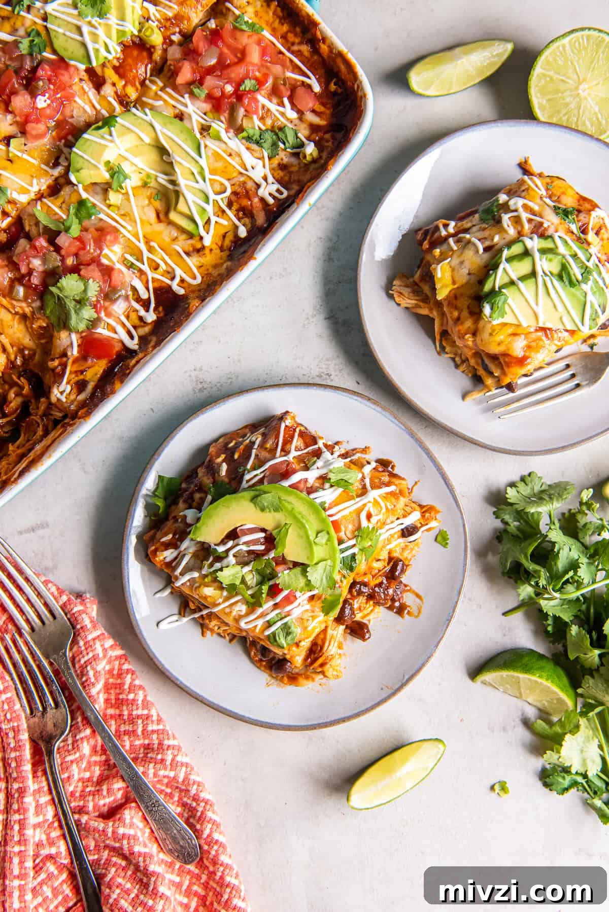 Two servings of chicken enchilada casserole on white plates with the casserole next to them.