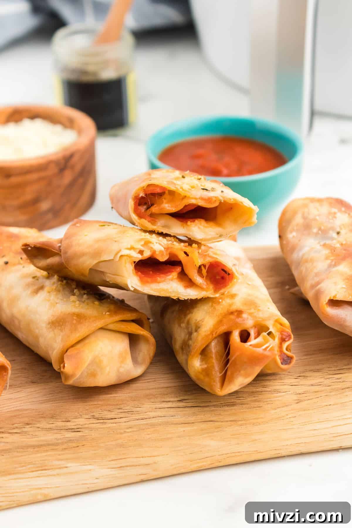Cut open pizza egg rolls showing sauce, cheese and pepperoni.