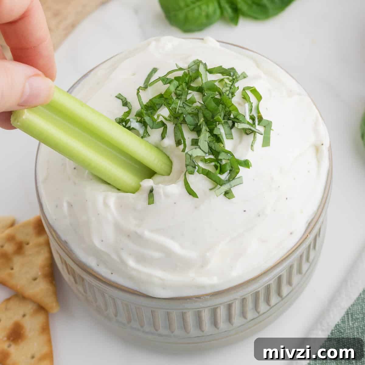 Celery dipped in a creamy cottage cheese dip topped with basil.