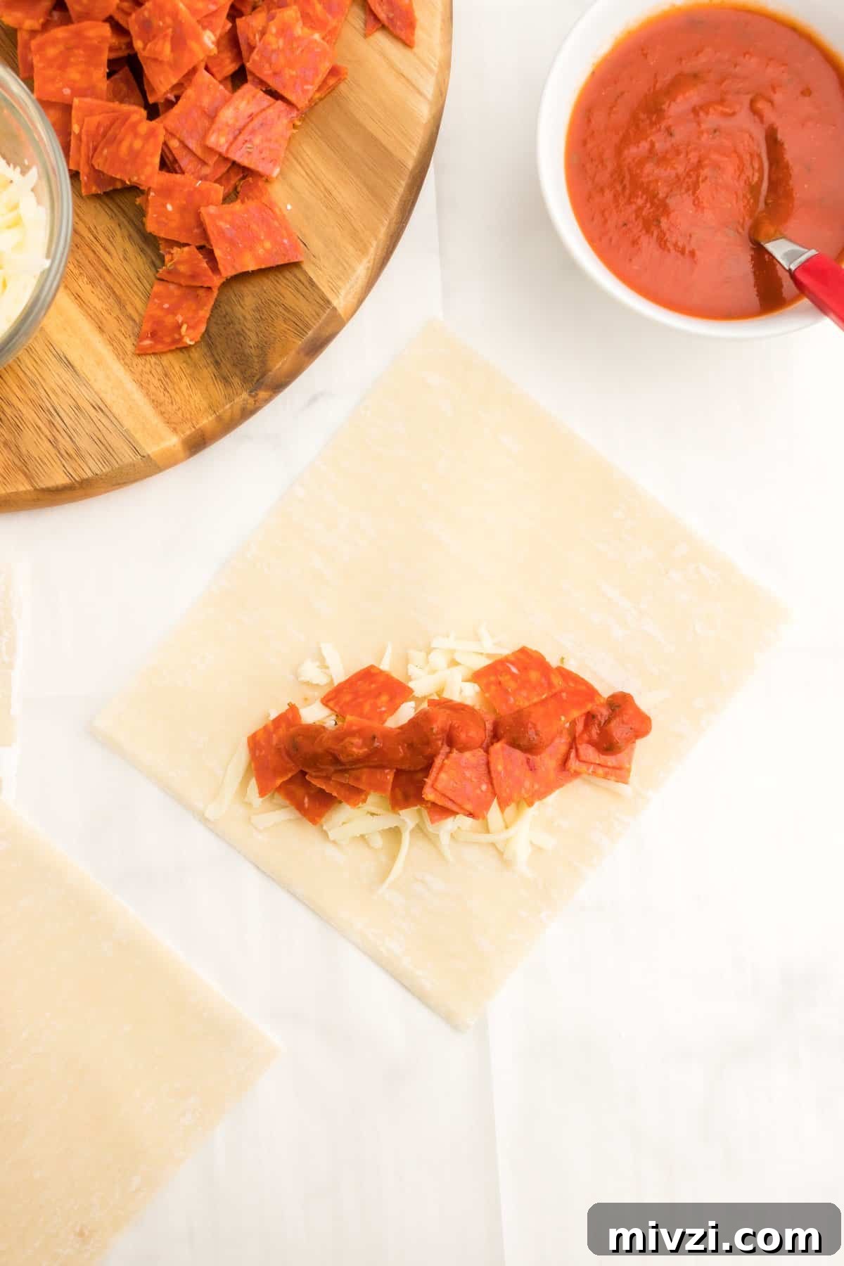 An egg roll wrapped laid out and topped with pepperoni and cheese.