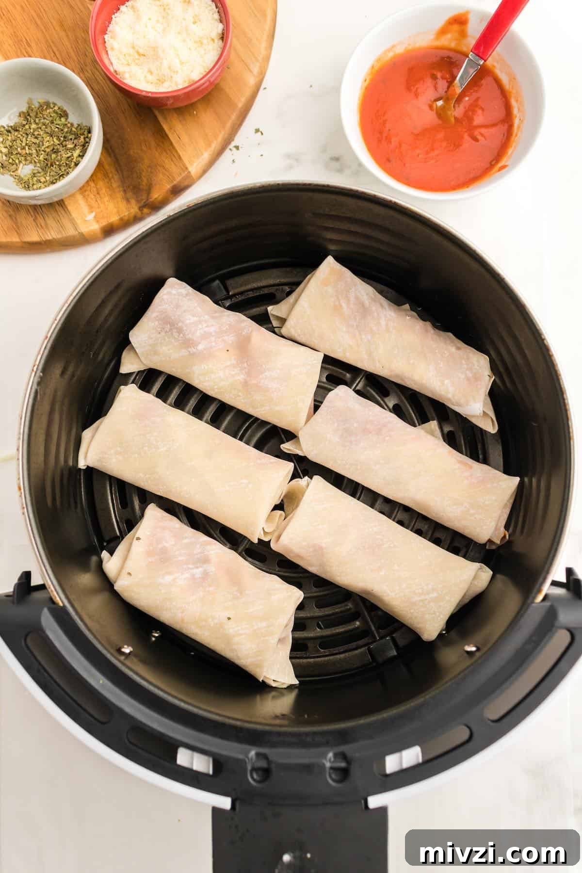 An air fryer basket filled with six pizza eggrolls.