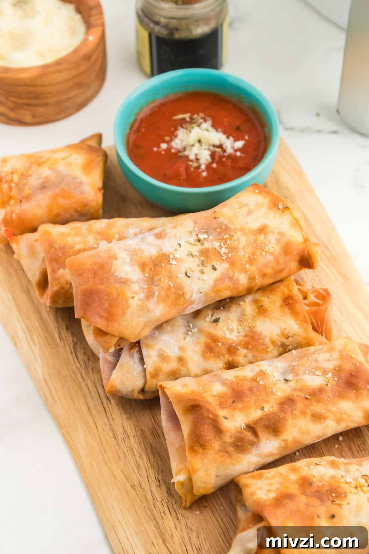 A tray of cooked golden brown pizza egg rolls.