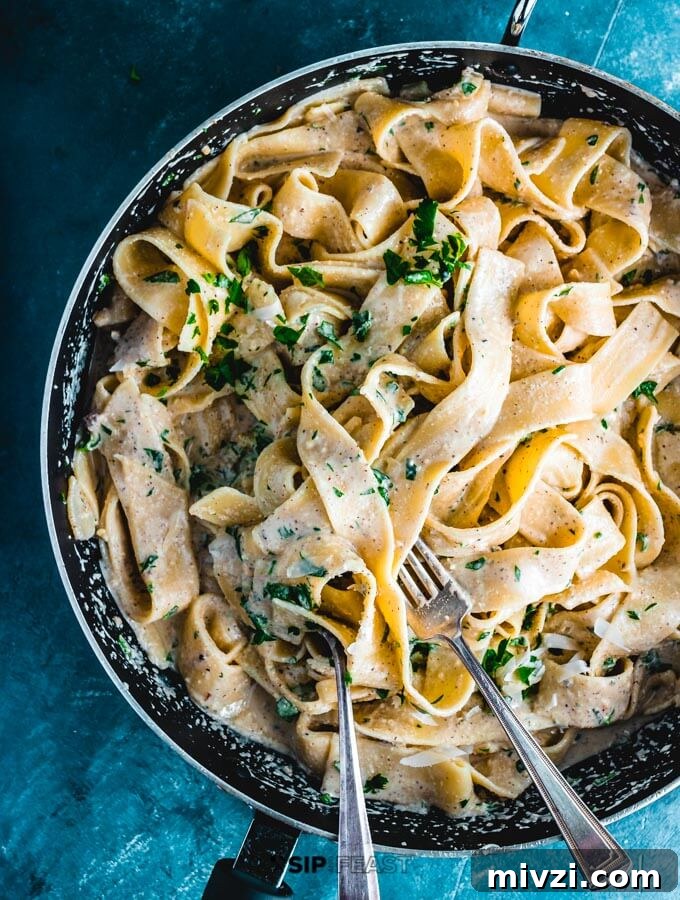 Walnut sauce mixed with pasta in pan.