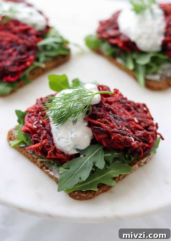 An open sandwich with beet and celery root cakes and creamy sauce on a plate