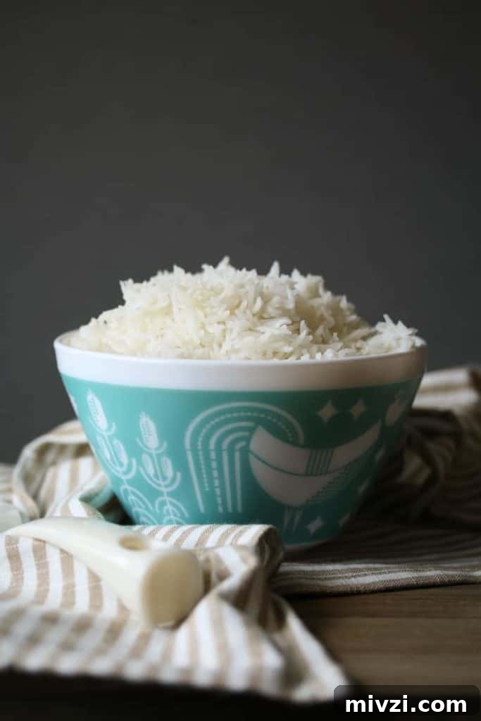 White rice in a white and teal pyrex bowl on a striped towel