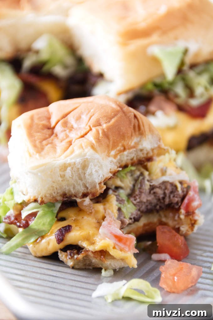 smashburger slider with a bit out of it, burger toppings spilling out onto sheet pan.