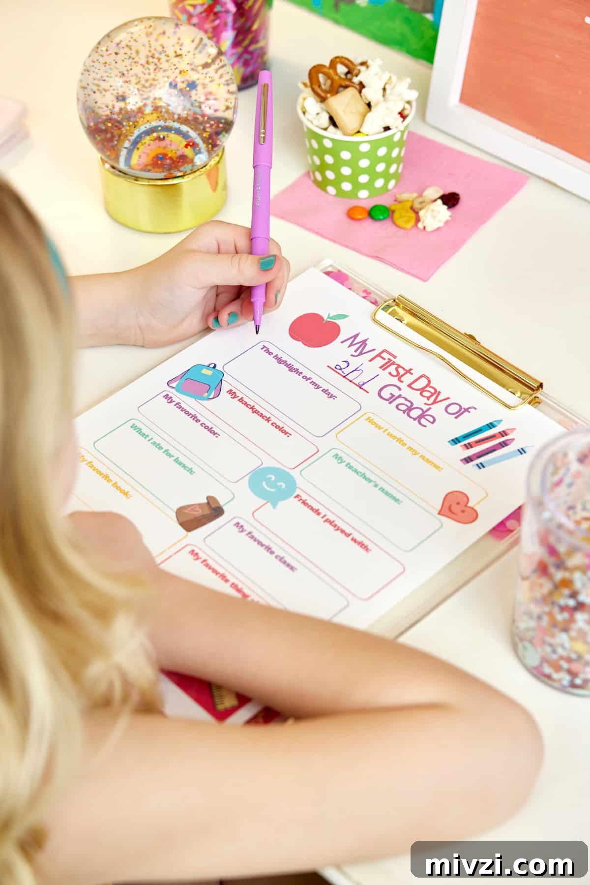 A young girl filling out a My First Day questionnaire and eating a popcorn snack mix.