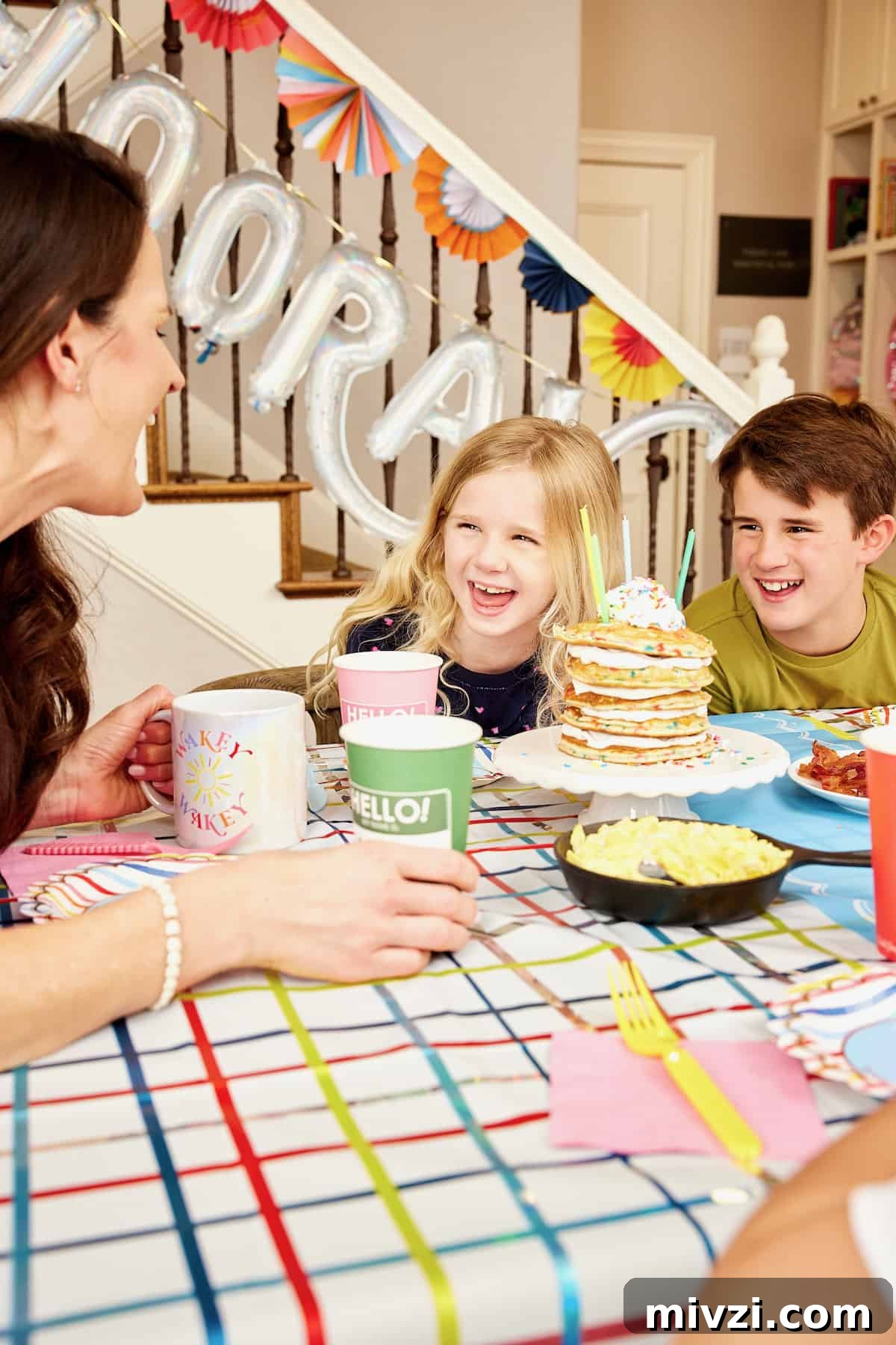 A family of a mother and four kids enjoying breakfast on the first day of school with colorful hanging paper decorations in the background.