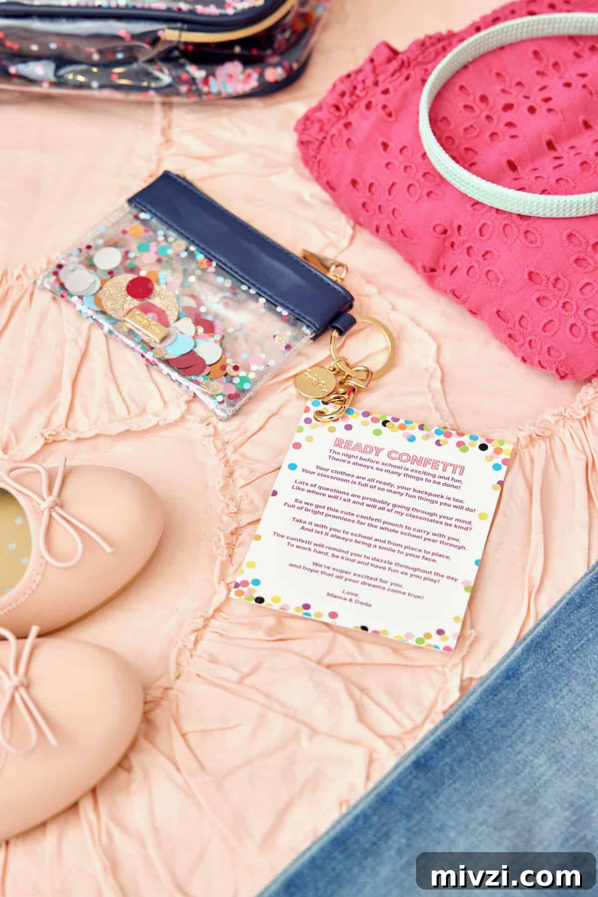 A small key chain pouch with glitter, a pair of child's pink ballet flats, and a bright pink eyelet lace child's shirt on a pale pink ruffled bedspread.