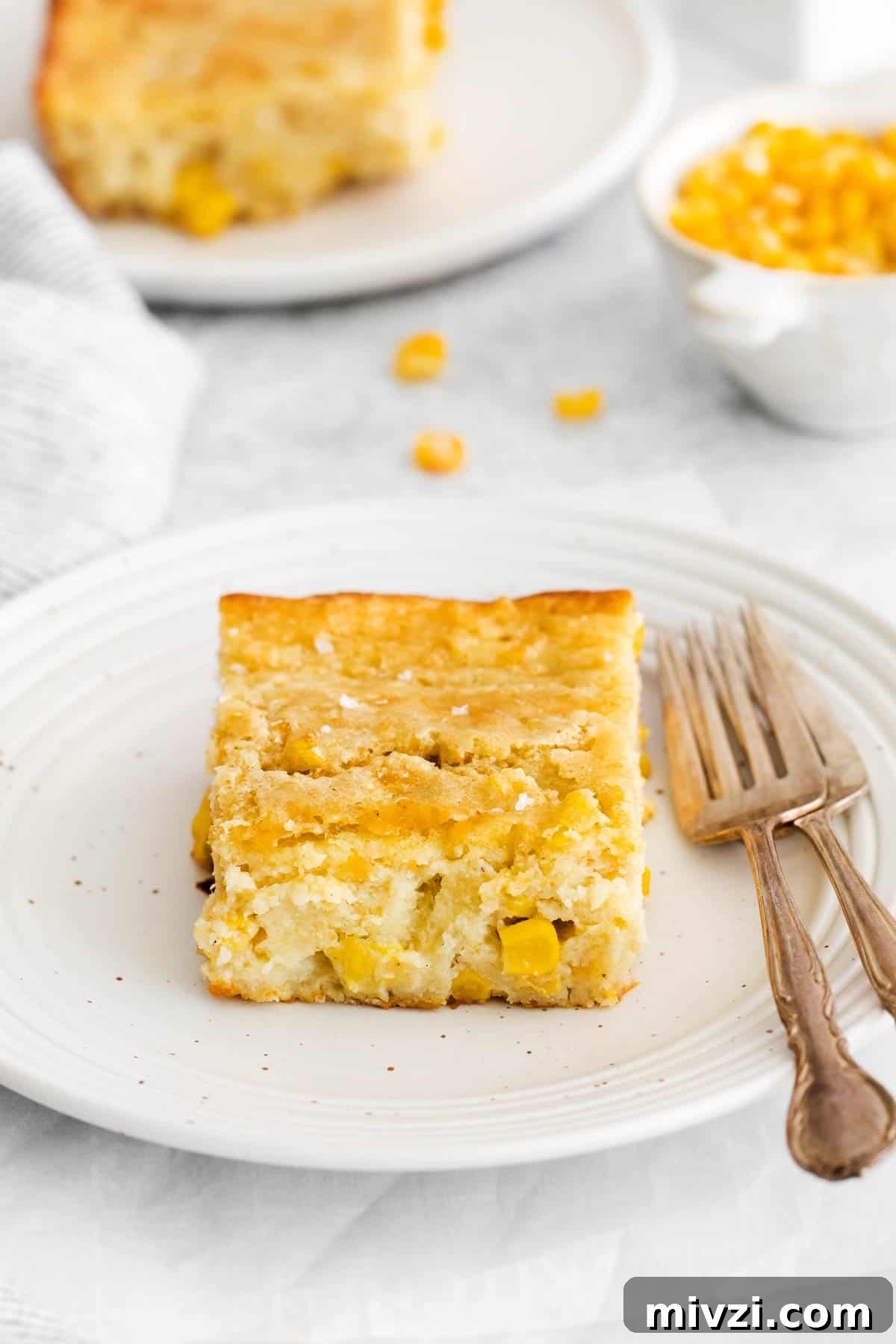 Cheesy Gluten-Free Corn Casserole Recipe for Every Occasion 10 A serving of corn casserole on a plate with a fork next to it