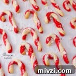 a batch of cookies that are shaped like candy canes on a baking sheet sprinkled with sugar.