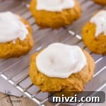 four iced pumpkin cookies on a cooling rack