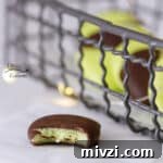 a wire tray with mint chocolate candies in it and one in front that has a bite taken out of it.