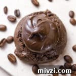 looking down on a chocolate cookie that's covered with frosting and coffee beans are around it.