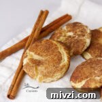 square crop of cookies on a cloth napkin with cinnamon sticks.