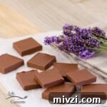 square crop of Two Ingredient Peanut Butter Chocolate Fudge on parchment paper with lavender in the back