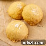 three cookies topped with sea salt on a piece of parchment paper.