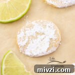 a cookie coated in powdered sugar with slices of lime around it.