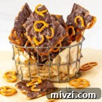 square crop of pieces of bark in a wire container with a piece in front and some broken pretzels around