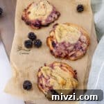 looking down on three blackberry cookies on a piece of parchment paper.