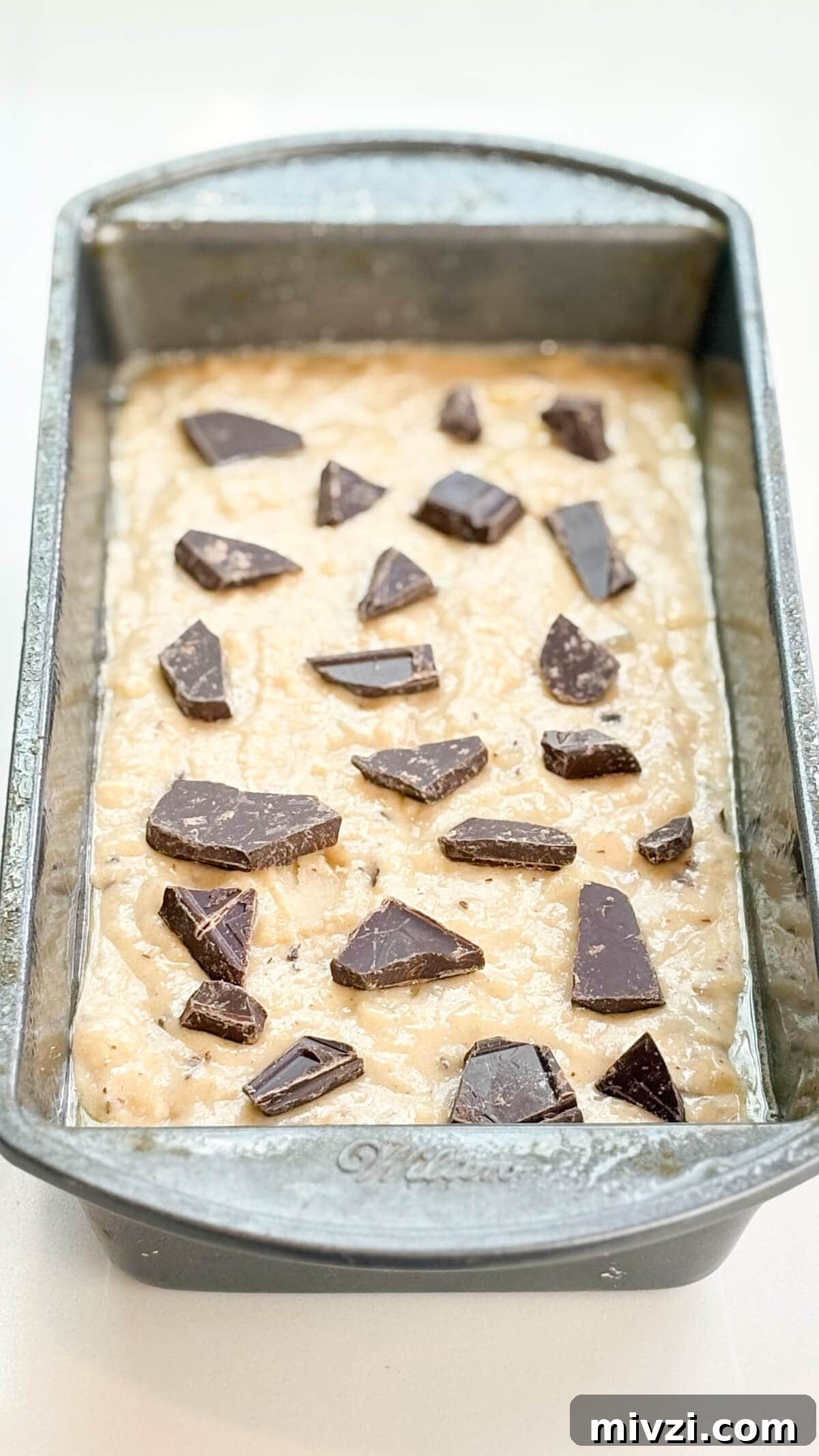 Chocolate Chunk Banana Bread Recipe with Gooey Chocolate Chunks 9 Batter in loaf pan with chocolate chunks on top.
