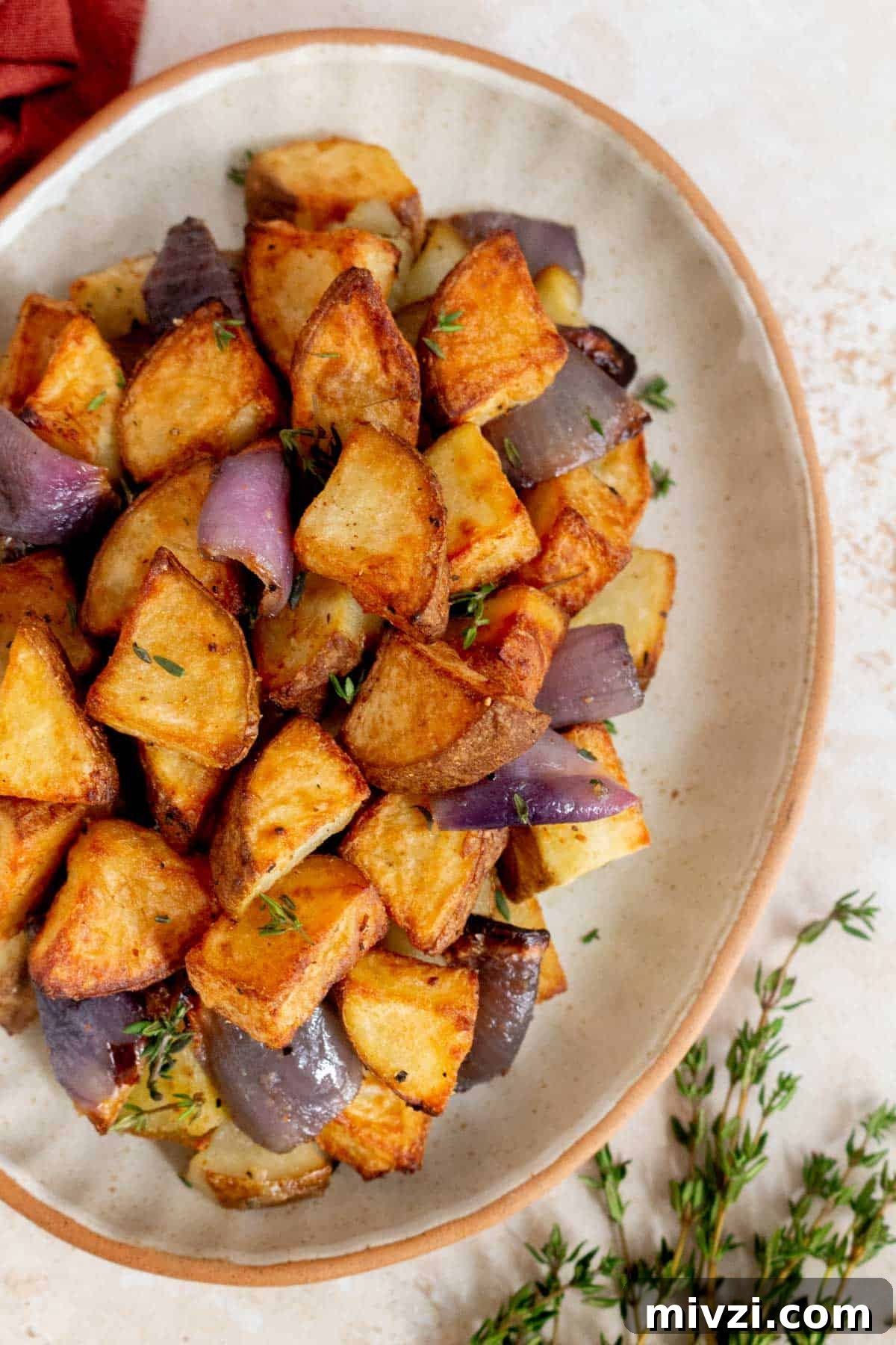 Overhead view of air fryer potatoes and onions on a plate.