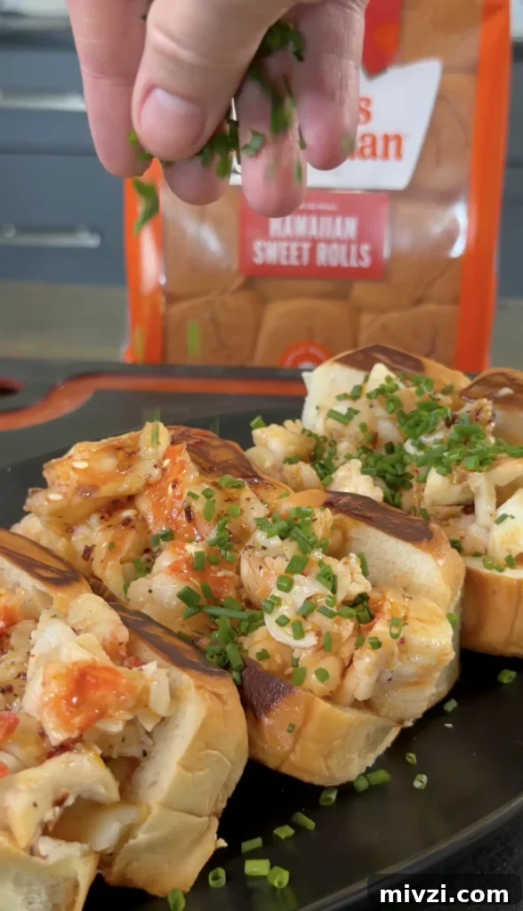 Spicy Hot Honey Lobster Rolls with Chili Crisp 2 Hot honey butter lobster rolls on dark plate, topped with fresh chives and caramelized onions