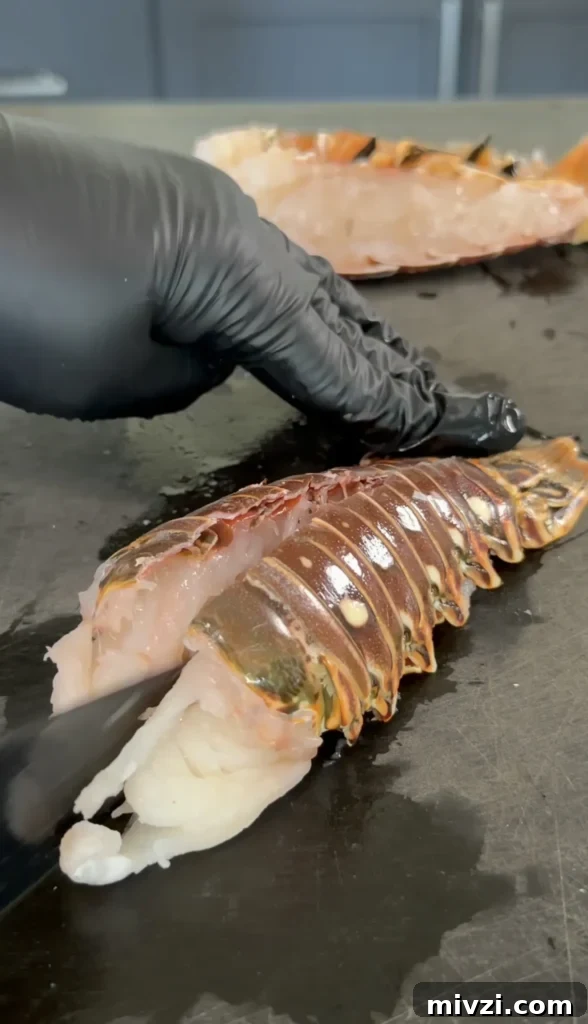 Spicy Hot Honey Lobster Rolls with Chili Crisp 8 Chef in black gloves preparing fresh lobster tail with knife on stainless steel counter for hot honey butter lobster rolls