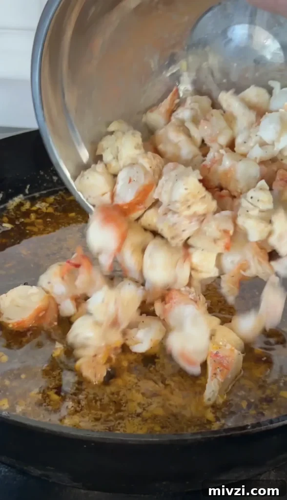 Spicy Hot Honey Lobster Rolls with Chili Crisp 9 Fresh cooked lobster meat being poured from a pot into a sizzling pan with butter for hot honey butter lobster rolls