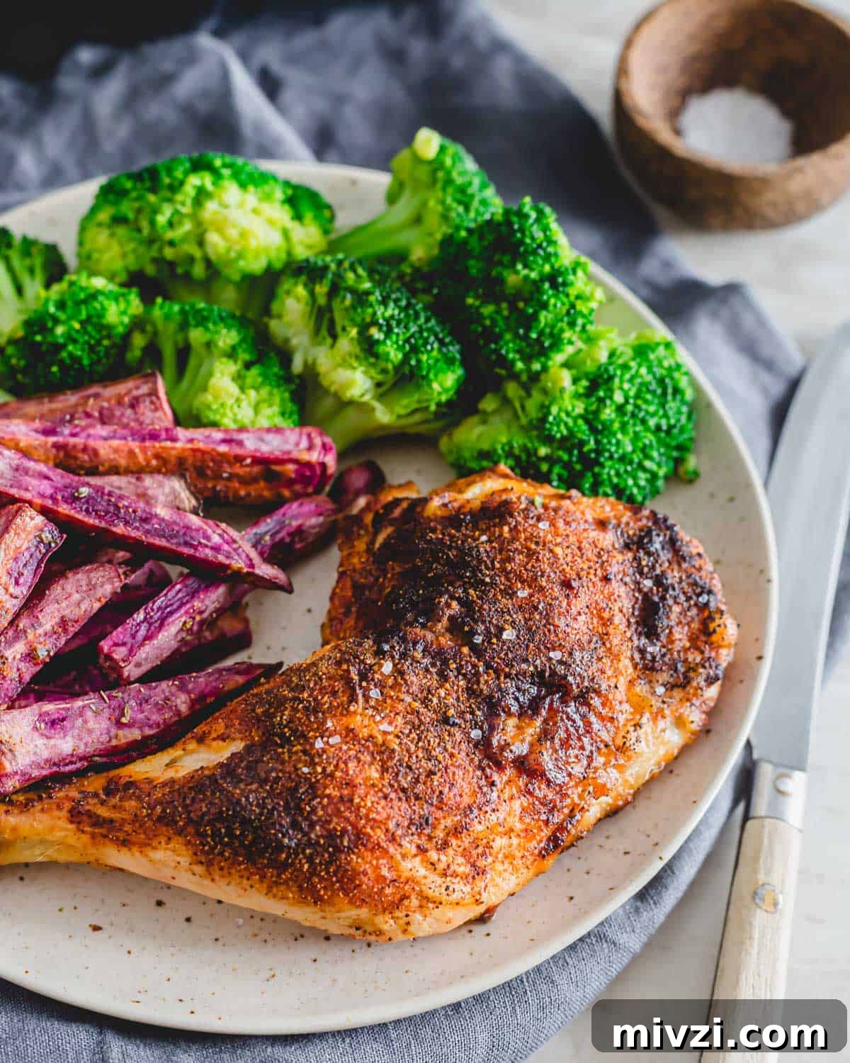 Spice rubbed air fryer chicken leg quarters on a plate with broccoli and purple sweet potato fries. Spice rubbed air fryer chicken leg quarters on a plate with broccoli and purple sweet potato fries.