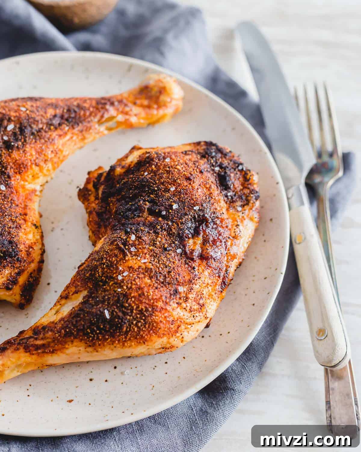 Crispy air fried chicken leg quarters with spice rub and coarse salt on a plate. Crispy air fried chicken leg quarters with spice rub and coarse salt on a plate.