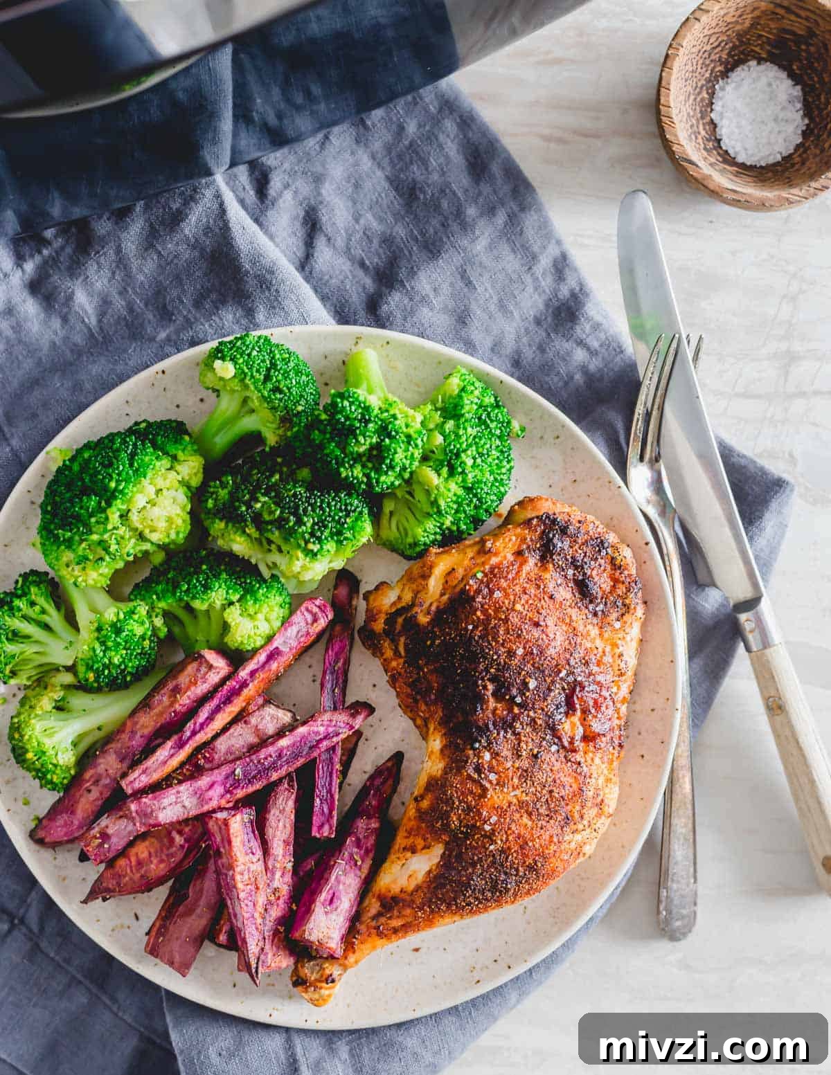 Chicken leg quarters roasted in the air fryer on a plate with broccoli and sweet potato fries. Chicken leg quarters roasted in the air fryer on a plate with broccoli and sweet potato fries.