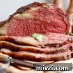 A smoked prime rib on a cutting board, sliced, with herbed butter.