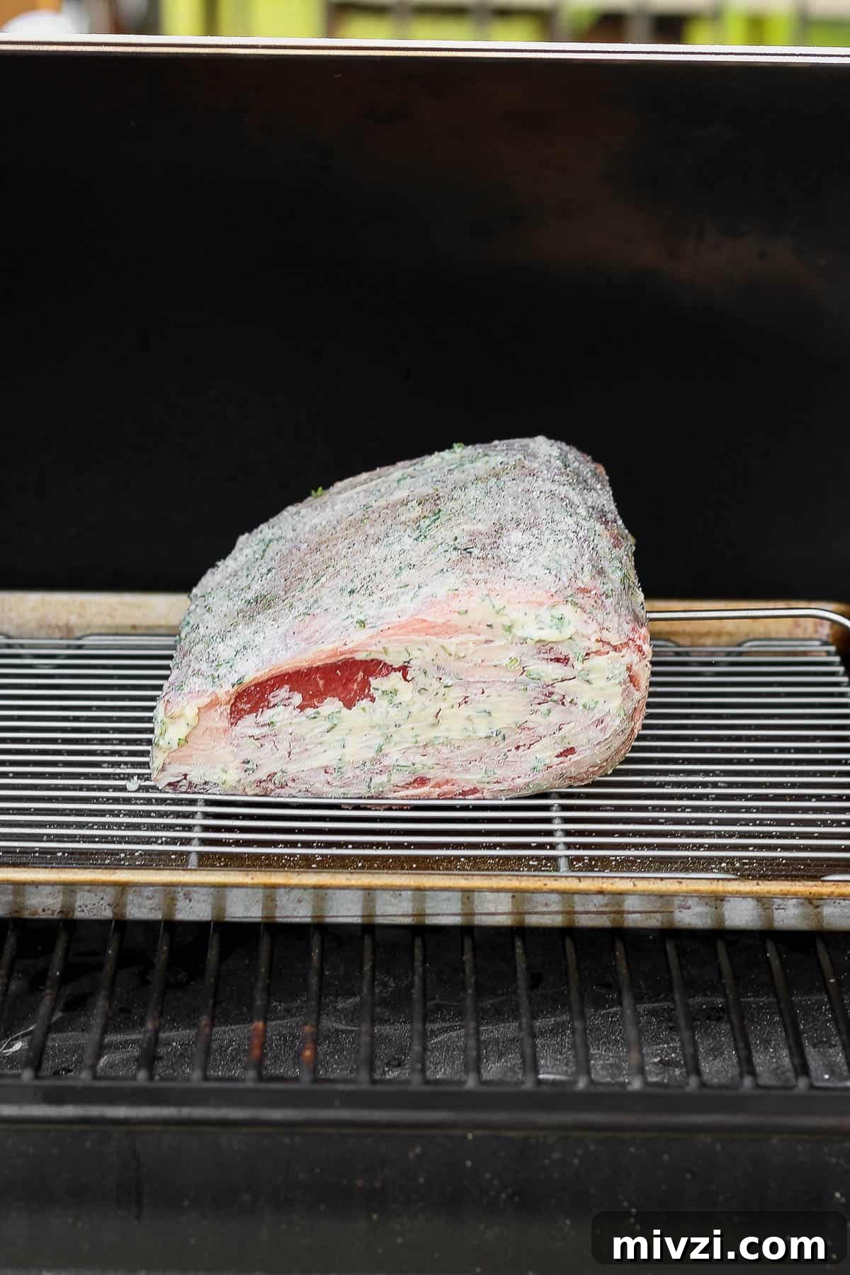 Prime rib on a baking sheet with a wire rack on the smoker.