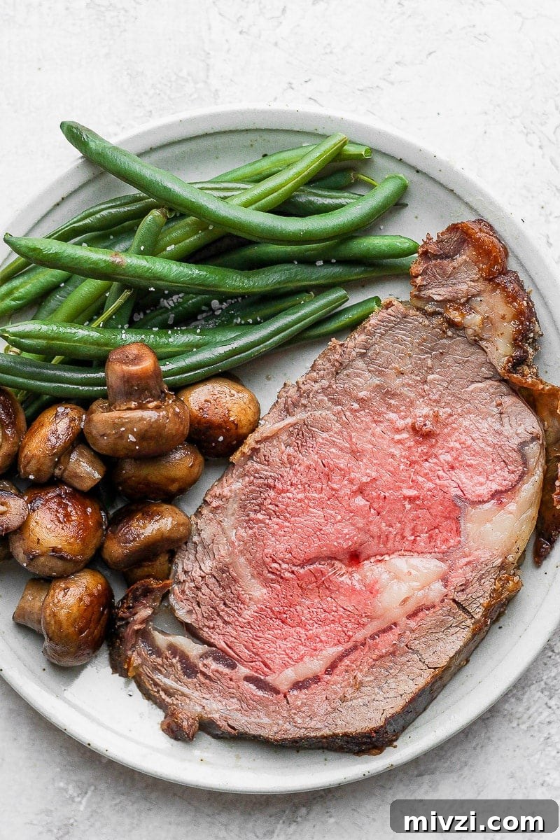 A slice of prime rib on a plate with mushrooms and green beans.