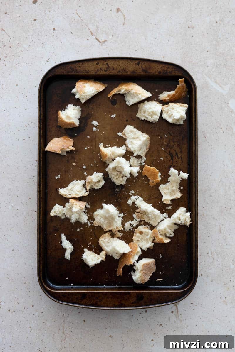 Torn chunks of bread on a baking sheet.