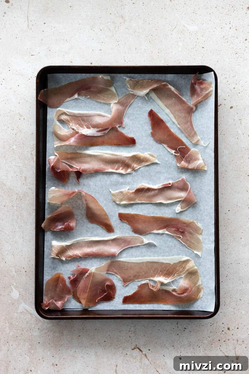 Prosciutto spread on a baking sheet lined with parchment paper.