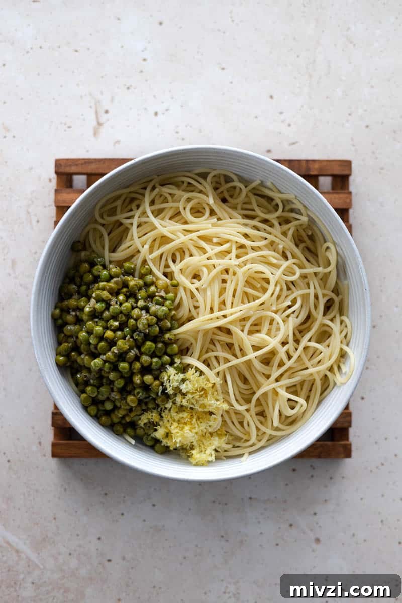 Pasta, peas and lemon zest in a bowl ready to mix.