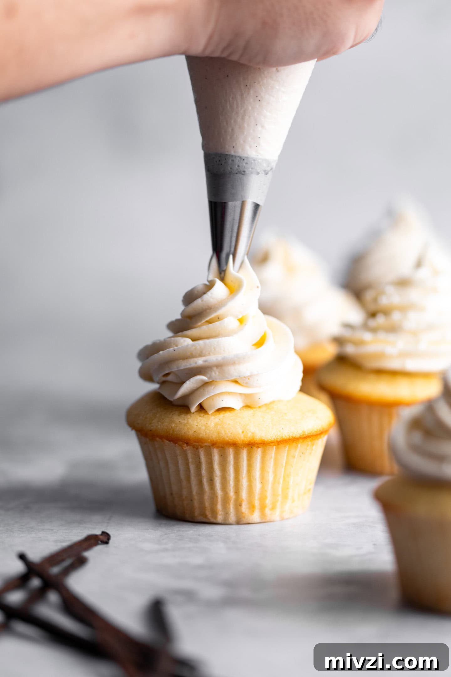 Quick Double Vanilla Buttercream Recipe in 5 Minutes 3 Double vanilla buttercream being piped on top of vanilla bean cupcake.