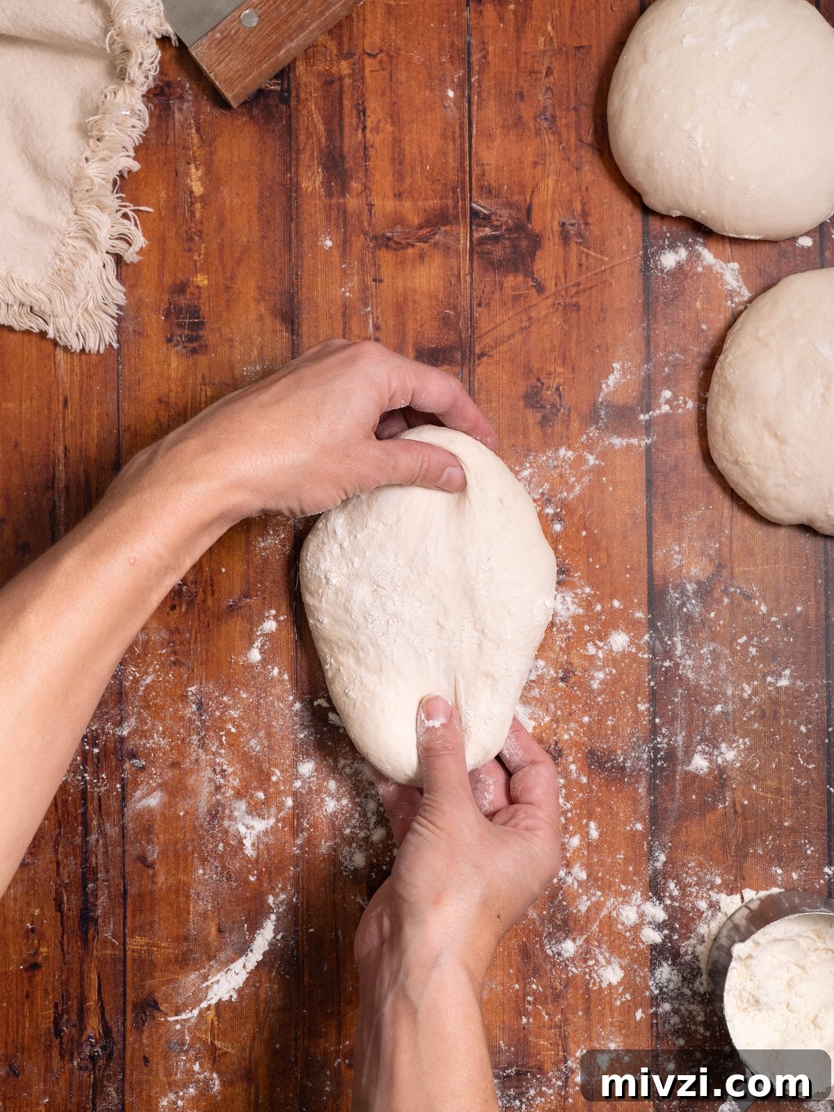 How to Make Classic Sourdough Baguettes at Home 5 Pulling a ball of bread dough into an oval shape