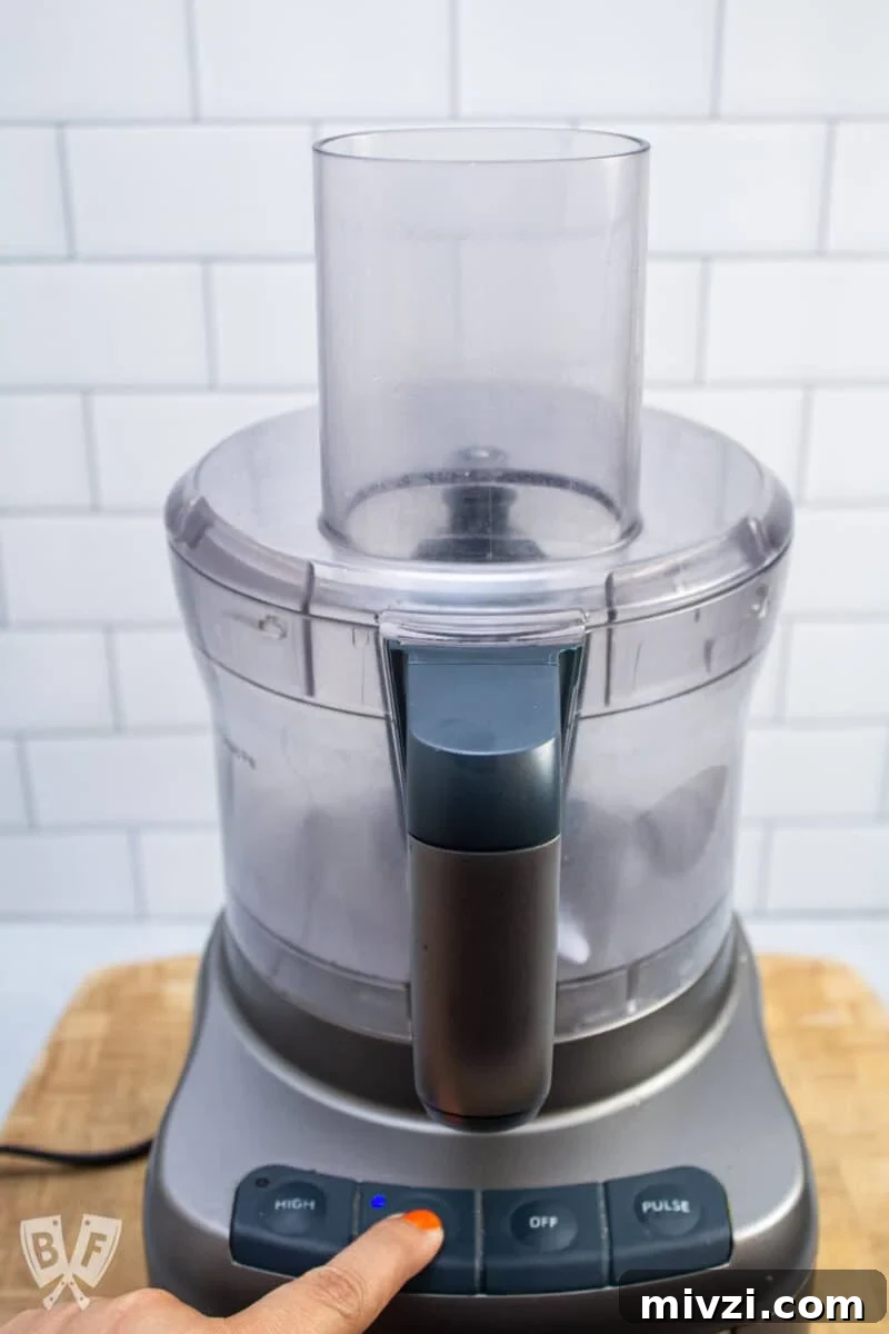 Classic Hummus from Canned Chickpeas – Quick Authentic Recipe 13 Turning a food processor on low speed.