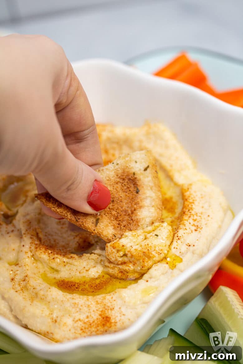 Classic Hummus from Canned Chickpeas – Quick Authentic Recipe 3 Pita chip scooping up hummus.