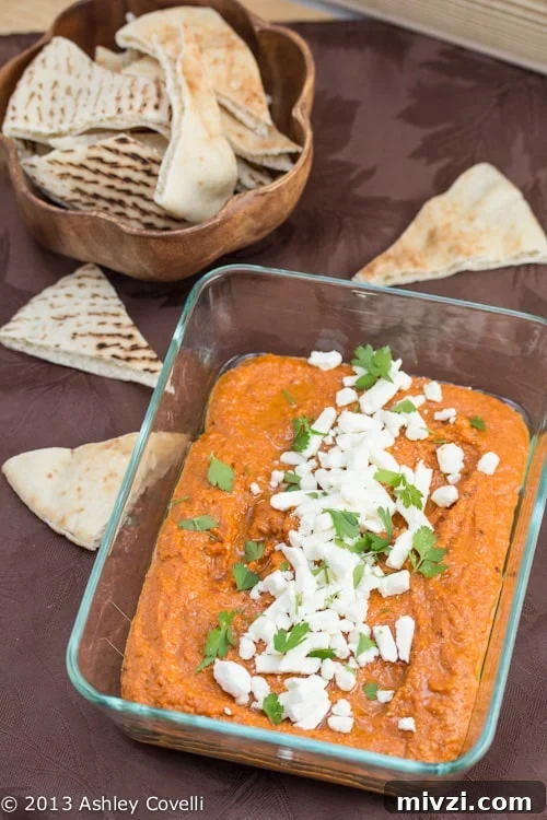 Classic Hummus from Canned Chickpeas – Quick Authentic Recipe 18 Muhammara in a serving dish topped with feta cheese alongside pita bread.